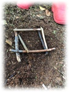 A square made from twigs, lying flat on the ground outdoors
