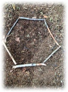 A hexagon made from sticks, lying flat on the ground outdoors